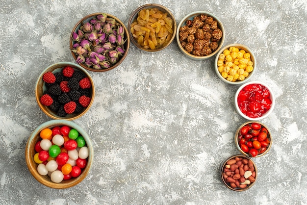 Vista superior de diferentes dulces caramelos pasas y nueces sobre fondo blanco galleta de golosinas de azúcar dulce