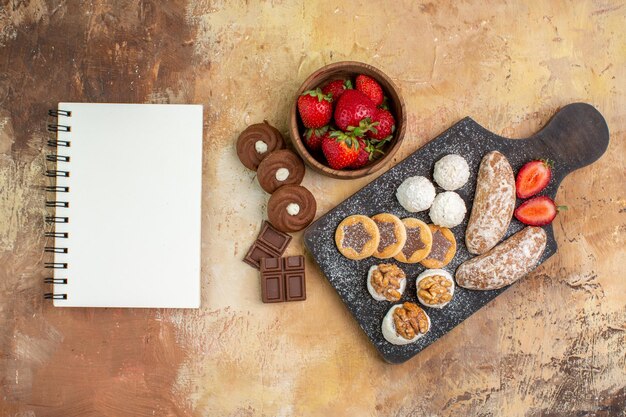 Vista superior de diferentes dulces con galletas y frutas en el escritorio de luz