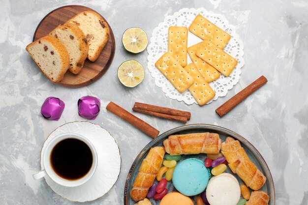 Vista superior de diferentes dulces tortas y caramelos con taza de té en blanco