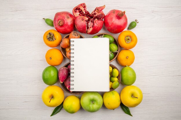 Vista superior de diferentes frutas de composición de frutas frescas con bloc de notas sobre fondo blanco.