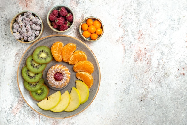 Vista superior de diferentes frutas composición frutas frescas y en rodajas con pastel sobre fondo blanco frutas suaves vitamina madura salud