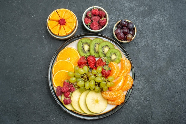 Foto gratuita vista superior de diferentes frutas composición frutas frescas y en rodajas sobre fondo oscuro salud frutas frescas maduras suave