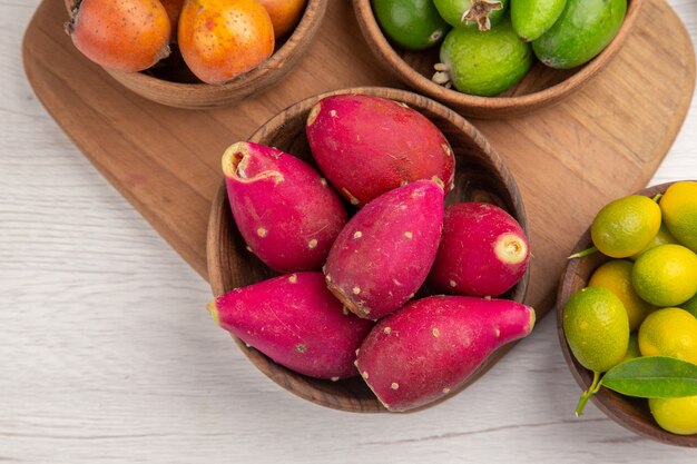 Vista superior de diferentes frutas feijoas bayas y otras frutas dentro de placas sobre fondo blanco color exótico de alimentos maduros