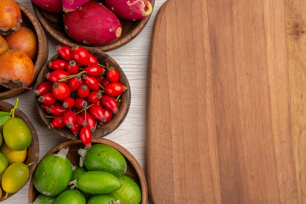 Vista superior de diferentes frutas feijoas y otras frutas dentro de placas sobre fondo blanco, color de salud tropical, árbol de bayas exóticas maduras