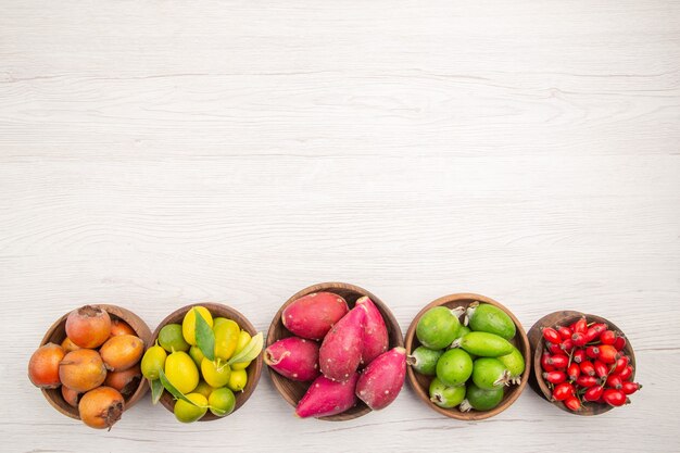 Vista superior de diferentes frutas frescas dentro de las placas en el escritorio blanco exótico tropical dieta madura color vida sana