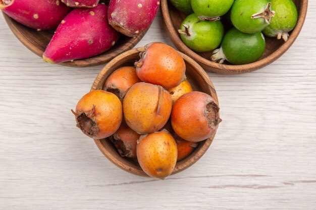 Vista superior de diferentes frutas frescas dentro de placas sobre fondo blanco exótica dieta madura tropical color vida sana