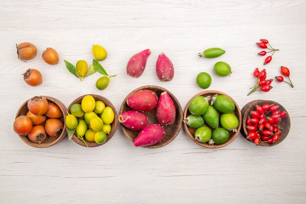 Vista superior de diferentes frutas frescas dentro de placas sobre fondo blanco exótica dieta madura tropical vida sana