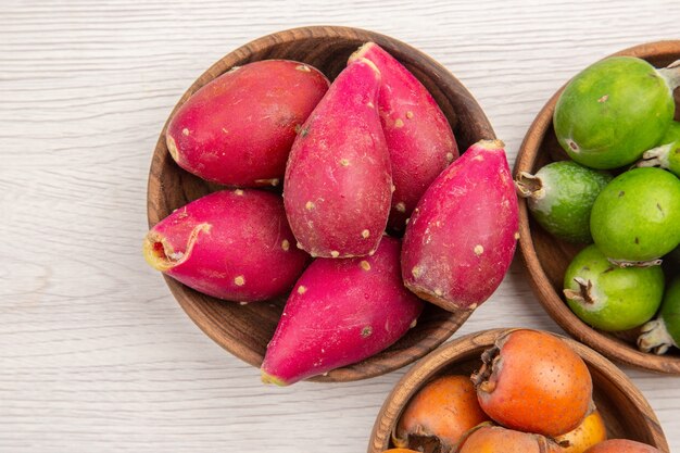 Vista superior de diferentes frutas frescas dentro de placas sobre fondo blanco fruta dieta tropical color exótico vida sana