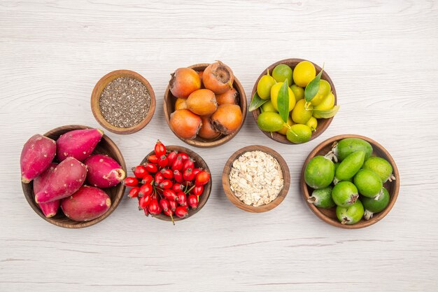 Vista superior de diferentes frutas frescas dentro de placas sobre fondo blanco vida sana madura dieta de color tropical