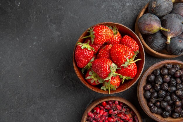 Vista superior de diferentes frutas frescas dentro de placas sobre fondo oscuro