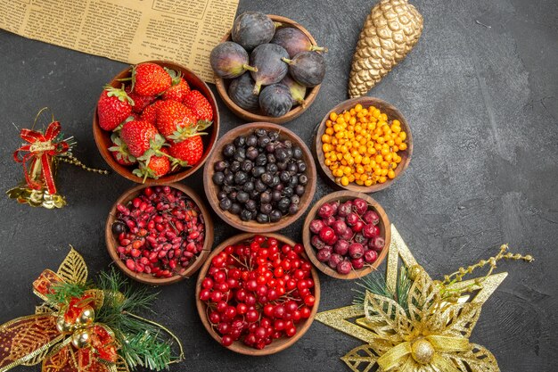 Vista superior de diferentes frutas frescas dentro de placas sobre fondo oscuro