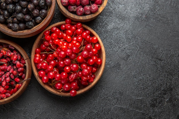 Vista superior de diferentes frutas frescas dentro de placas sobre fondo oscuro