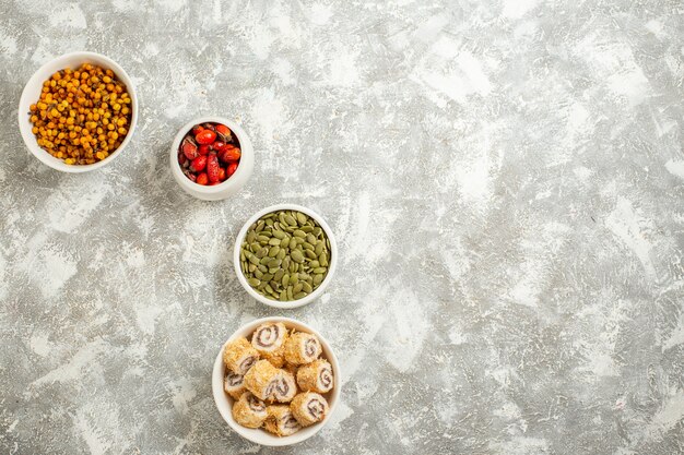 Vista superior de diferentes frutas con semillas y panecillos dulces sobre un fondo blanco.