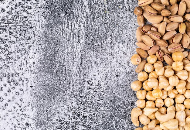 Vista superior diferentes frutos secos con almendras y avellanas en la mesa de piedra oscura