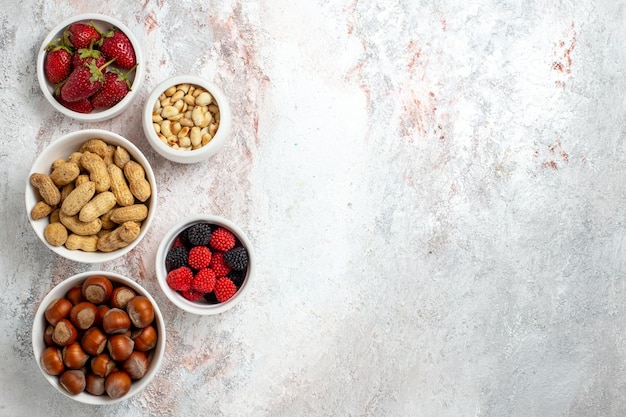 Foto gratuita vista superior de diferentes frutos secos avellanas cacahuetes y confituras sobre superficie blanca