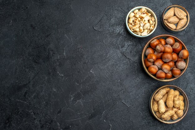 Vista superior de diferentes frutos secos, avellanas y cacahuetes en el fondo gris planta alimenticia de nuez snack nuez