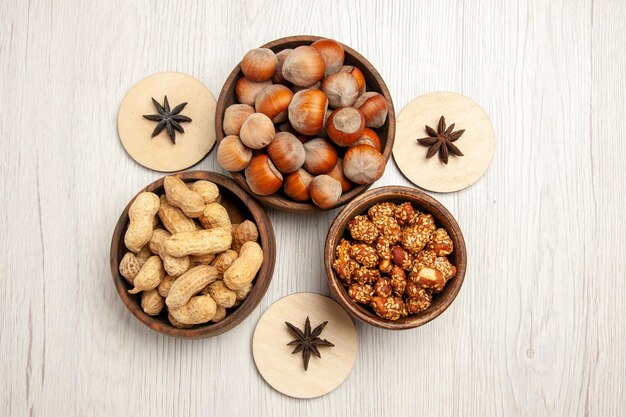 Vista superior de diferentes frutos secos dentro de pequeñas ollas en el escritorio blanco snack nuez nuez avellana