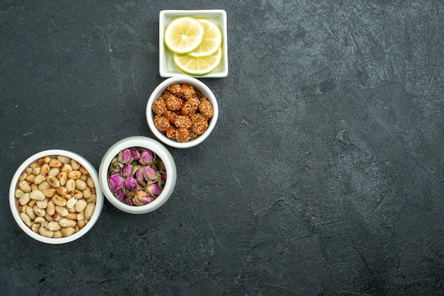 Vista superior de diferentes frutos secos con limón y caramelos en bocadillo de frutos secos de superficie oscura dulce