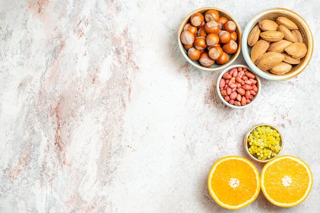 Vista superior de diferentes frutos secos con rodajas de naranja sobre fondo blanco aperitivo de frutos secos cítricos