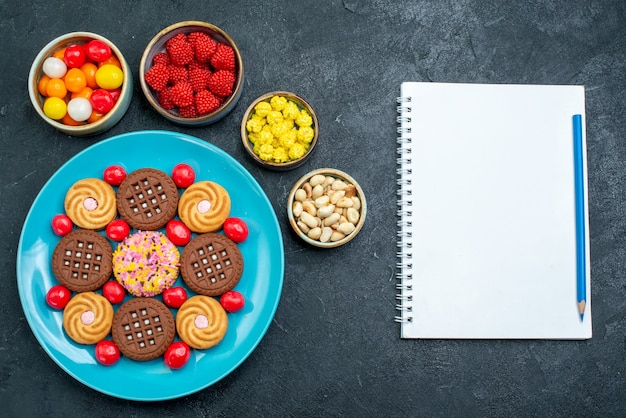 Foto gratuita vista superior de diferentes galletas de azúcar con caramelos en las galletas dulces de galletas dulces de azúcar de superficie gris