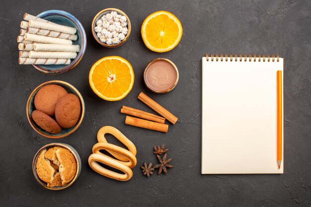 Vista superior diferentes galletas con naranjas en rodajas sobre fondo oscuro azúcar té galleta galleta fruta dulce