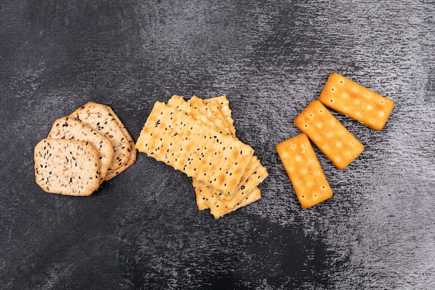 Vista superior de diferentes galletas en superficie oscura