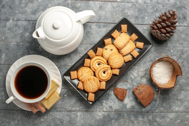 Vista superior de diferentes galletas con una taza de té en la superficie rústica gris pastel de galletas pastel azúcar galleta dulce