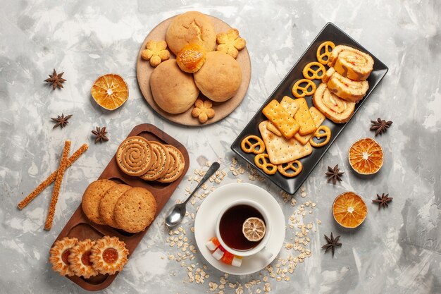 Vista superior de diferentes galletas con tortas y una taza de té en la superficie blanca galleta galleta azúcar hornear pastel pastel dulce
