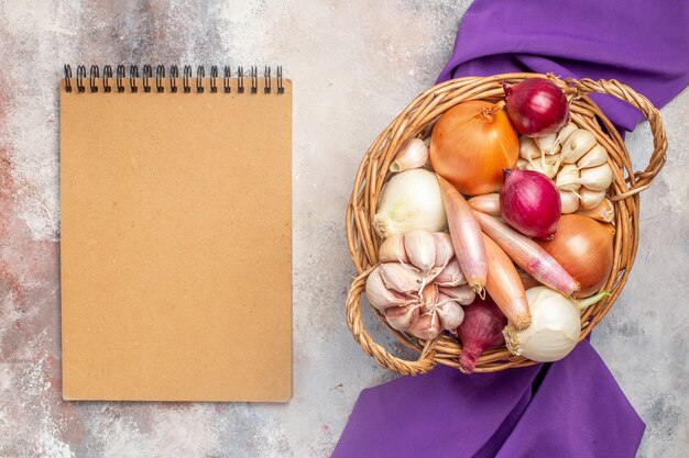 Vista superior de diferentes ingredientes cebollas y ajo dentro de la canasta con tejido morado