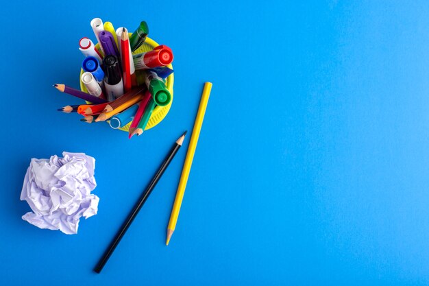 Vista superior de diferentes lápices de colores con rotuladores en el escritorio azul