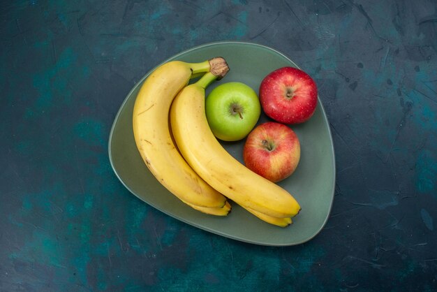 Vista superior de diferentes manzanas y plátanos de composición de frutas en el escritorio azul oscuro