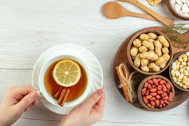 Vista superior diferentes nueces cacahuetes avellanas y nueces con taza de té en mesa blanca