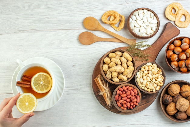 Vista superior diferentes nueces cacahuetes avellanas y nueces con taza de té en mesa blanca