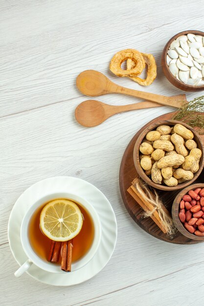 Vista superior diferentes nueces cacahuetes avellanas y nueces con taza de té en mesa blanca