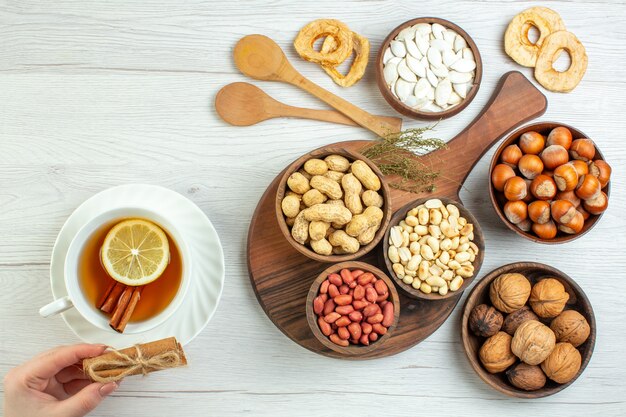 Vista superior diferentes nueces cacahuetes avellanas y nueces con taza de té en mesa blanca