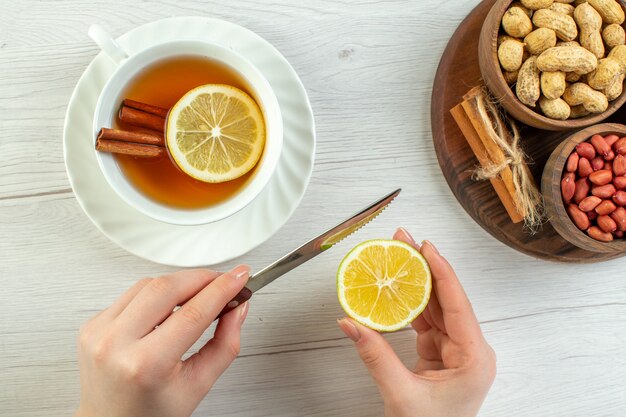 Vista superior diferentes nueces cacahuetes avellanas y nueces con taza de té en mesa blanca