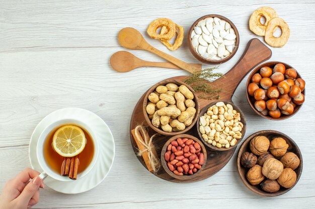 Vista superior diferentes nueces cacahuetes avellanas y nueces con taza de té en mesa blanca