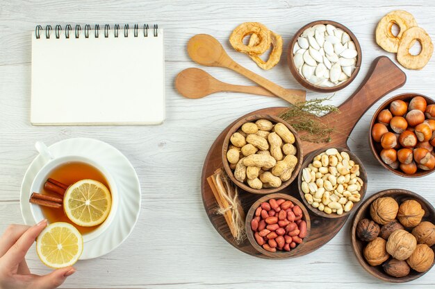 Vista superior diferentes nueces cacahuetes avellanas y nueces con taza de té en mesa blanca