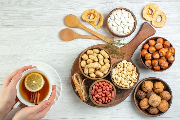 Vista superior diferentes nueces cacahuetes avellanas y nueces con taza de té en mesa blanca