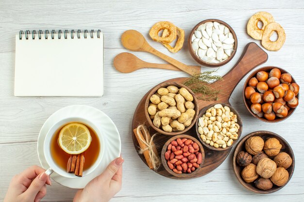 Vista superior diferentes nueces cacahuetes avellanas y nueces con taza de té en mesa blanca