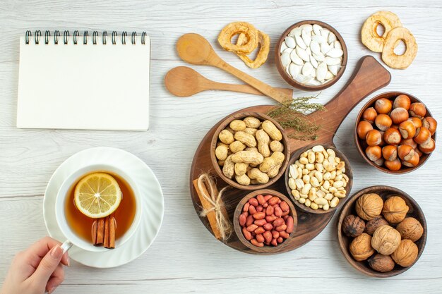 Vista superior diferentes nueces cacahuetes avellanas y nueces con taza de té en mesa blanca