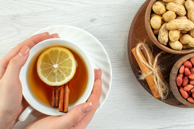 Vista superior diferentes nueces cacahuetes avellanas y nueces con taza de té en mesa blanca