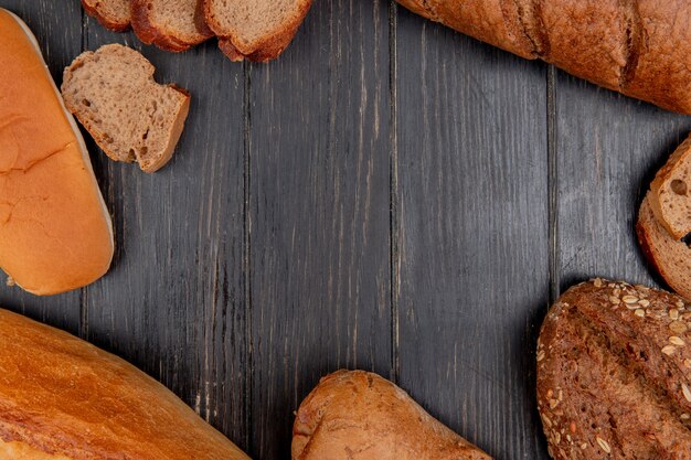 Vista superior de diferentes panes como sándwich de baguette de centeno negro sobre fondo de madera con espacio de copia