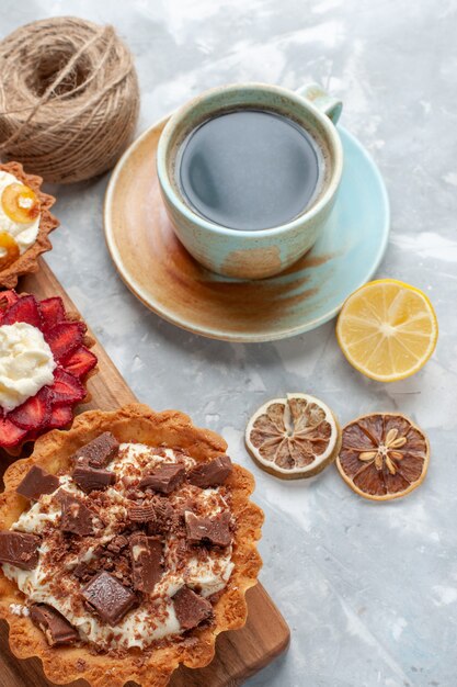 Vista superior de diferentes pasteles cremosos con chocolate y té de frutas en el escritorio blanco pastel hornear galletas fruta dulce azúcar