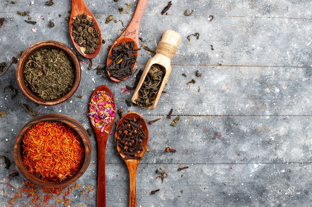 Vista superior de diferentes sabores secos de té fresco en el suelo gris planta de fruta de té sabor a flor