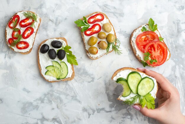 Vista superior de diferentes sándwiches sabrosos con pepinos, tomates y aceitunas sobre fondo blanco, almuerzo, comida horizontal, comida, pan, tostadas, hamburguesas, salud.