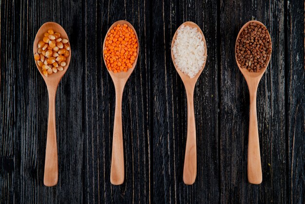 Vista superior de diferentes tipos de granos y semillas en cucharas de madera semillas de maíz lentejas rojas arroz y trigo sarraceno