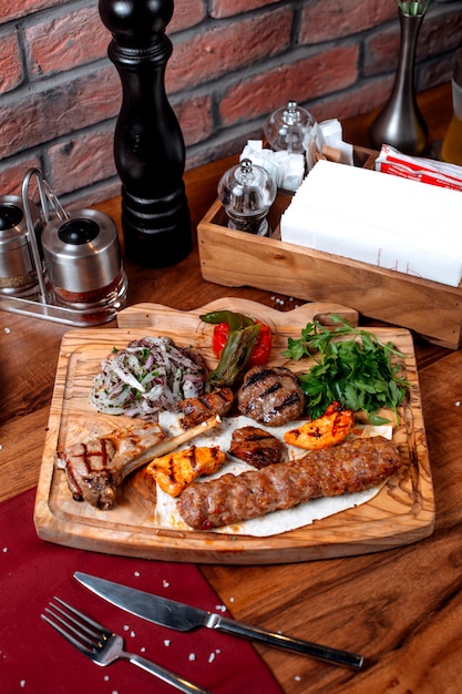 Vista superior de diferentes tipos de kebab con cebolla y hierbas sobre una tabla de madera