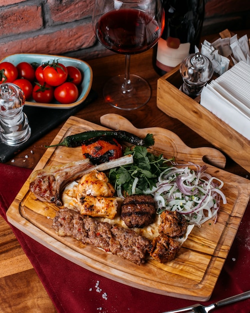 Vista superior de diferentes tipos de kebab con cebolla roja y hierba sobre una tabla de madera
