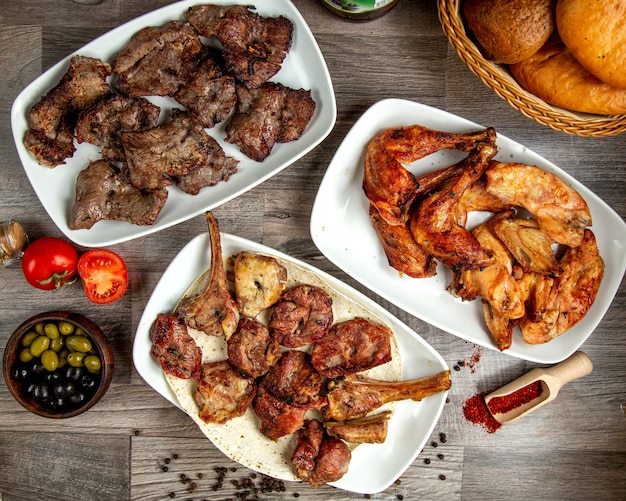 Vista superior de diferentes tipos de kebabas de ternera con pollo y costillas de cordero en una mesa de madera